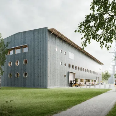 TUMorrow Factory Außenansicht: längliches Holzgebäude mit runden Fenstern im Grünen gelegen.