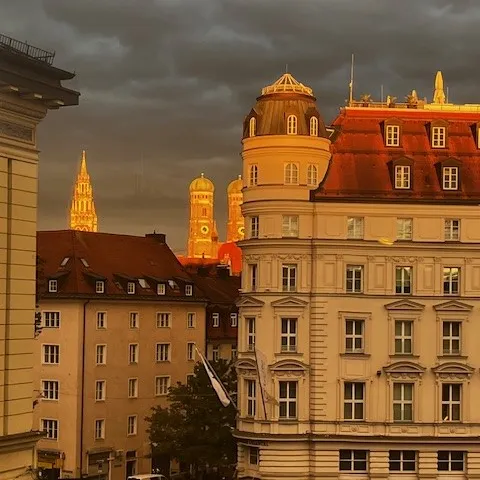 Blick vom Büro aus Richtung Frauenkirche im Sonnenaufgang. Man sieht rechts das Mandarin Oriental Hotel und im Hintergrund von der Sonne angeleuchtet die beiden Türme der Frauenkirche