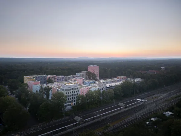 Sicht auf das Regensburger Viertel aus der Vogelperspektive im Sonnenaufgang. Im Vordergrund sieht man die Gleise mit der S-Bahnstation Frankenstadion.