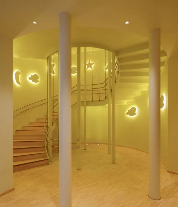 Treppenaufgang der Kinderoase mit Motivleuchten (Sonne, Mond, Sterne), beleuchtet, in gelb gehalten.